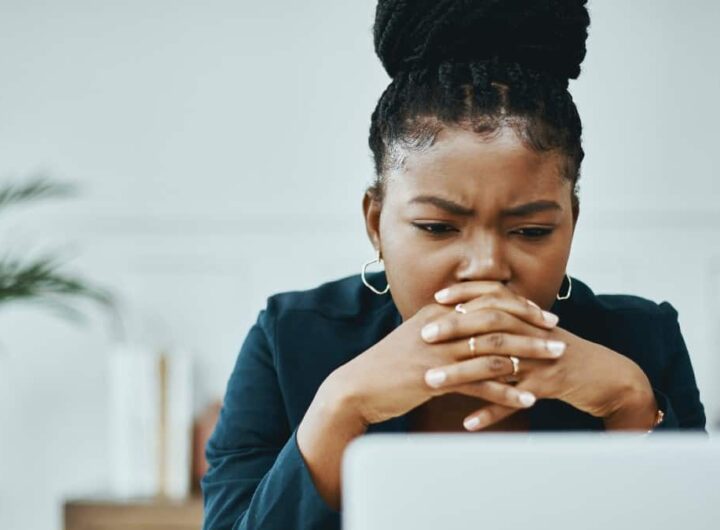 Young Black woman looking concerned while in front of her laptop